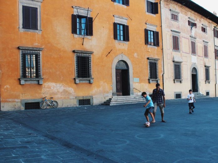 In tre giocano vicino a un edificio di cemento In tre giocano vicino a un edificio di cemento