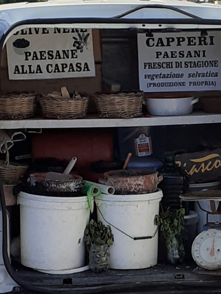 Olive nere, capperi e tant’altro. Eccoci tra i sapori del Salento. In questa immagine, i prodotti della terra esposti da un ambulante di Tricase nel suo mitico furgoncino Ape trasformato in negozio