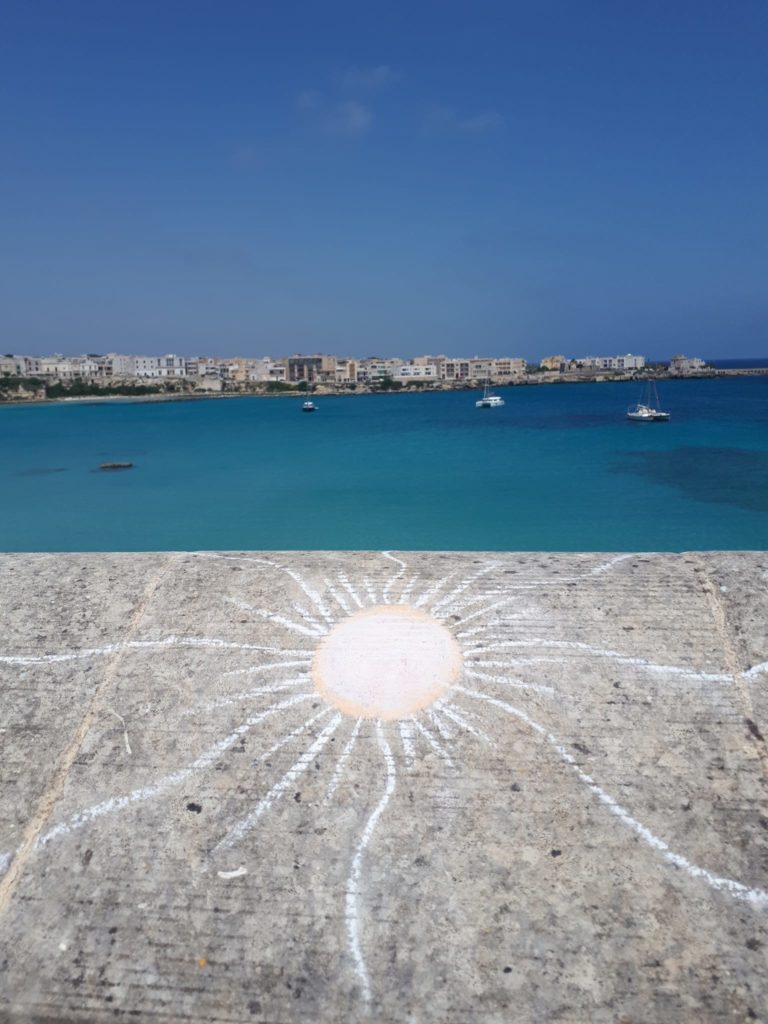 Panoramica del golfo d’Otranto. In primo piano, Il sole inciso sulla pietra da un artista ignoto che fa bella mostra in un tratto della balaustra dell’antica Fortezza