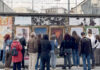 Schio diventa una galleria a cielo aperto: poster art in sei vie fino al 31 ottobre Poster art a Schio, visitatori osservano le opere affisse lungo una strada cittadina
