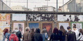 Schio diventa una galleria a cielo aperto: poster art in sei vie fino al 31 ottobre Poster art a Schio, visitatori osservano le opere affisse lungo una strada cittadina